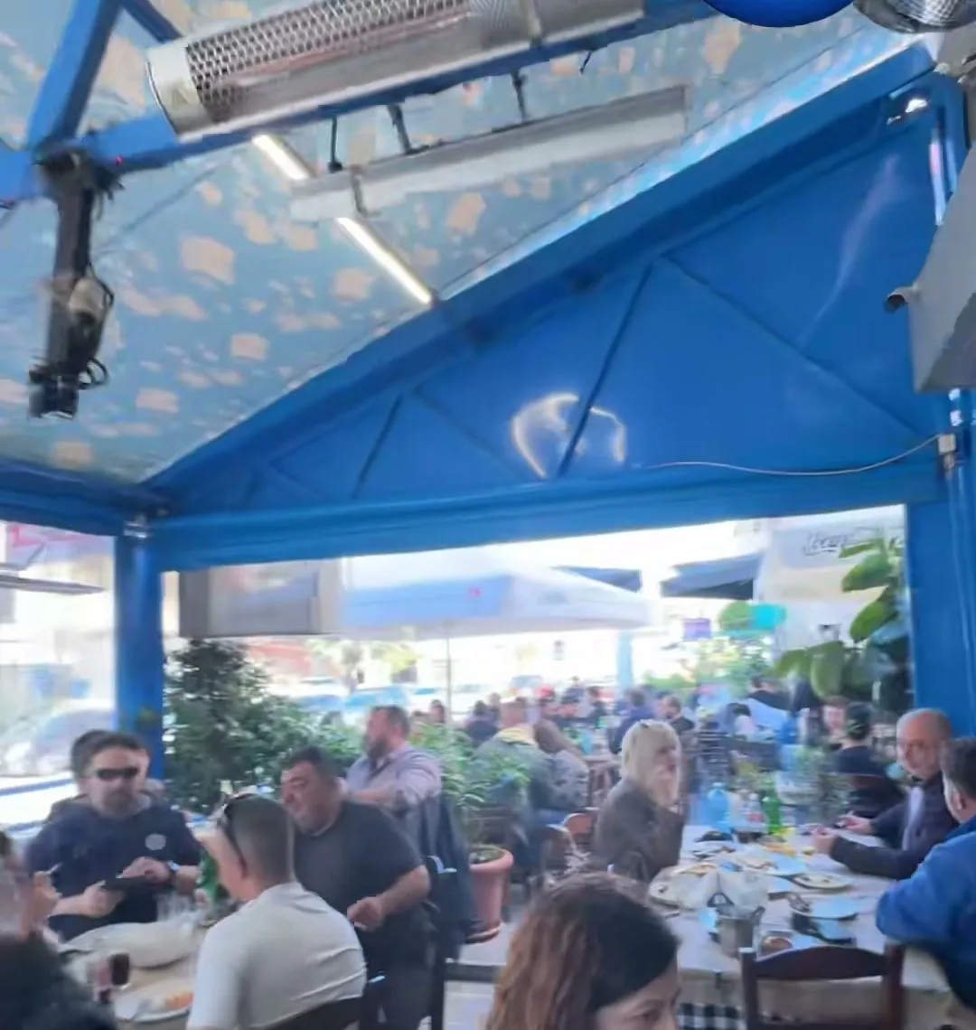 Η στεγασμένη βεράντα με τον ζωγραφισμένο ουρανό, γεμάτη κόσμο το μεσημέρι